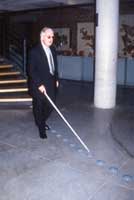 A visually impaired (blind) visitor uses the Tactdots tactile paving system to move in the museum. 